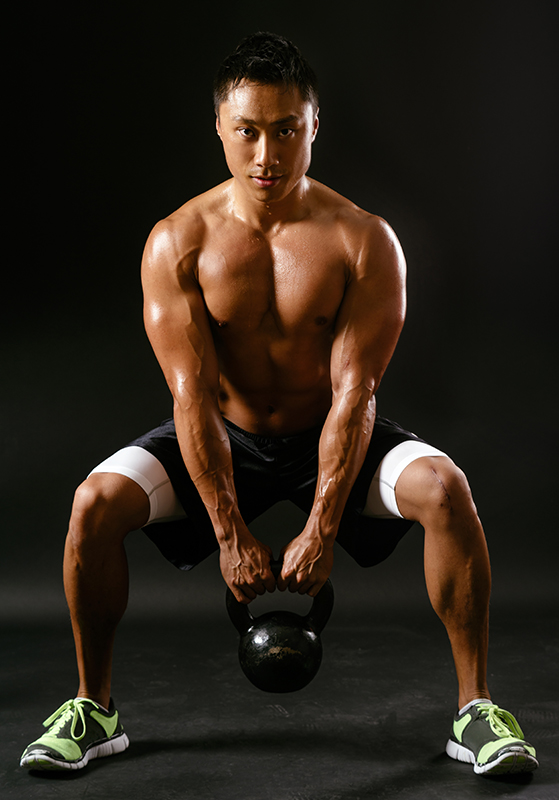 man does squat with kettlebell