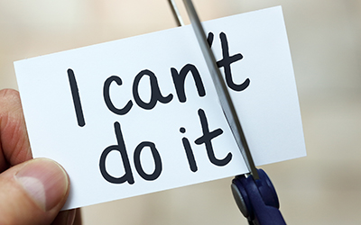 Person uses a pair of scissors to turn "I can't do it" written on a card into "I can do it"