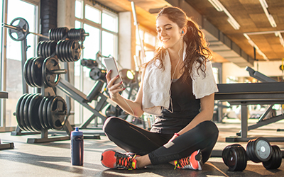 Woman watches video of workout on her phone during a rest period.