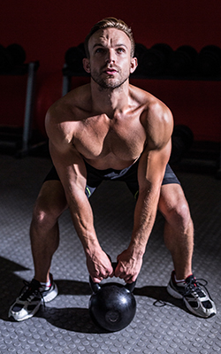 Man performs a deadlift using a kettlebell.