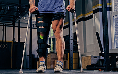 Athlete with brace on one leg and crutches engages in physical therapy.