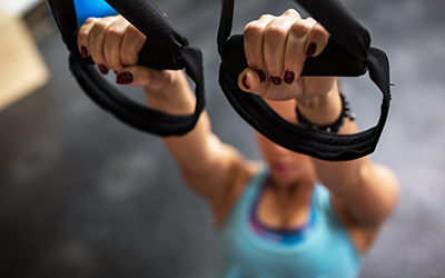 Woman uses a suspension system to perform an inverted row.