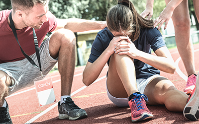 Runner deals with an injury on the track with coach and trainer by her side.