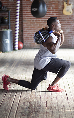 Man performs a lunge with a weighted bag over his shoulders.