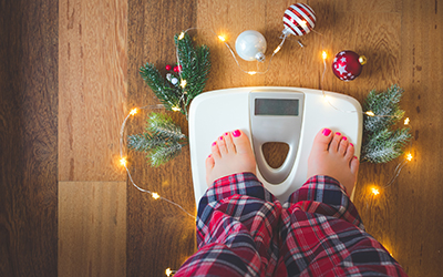 Person checks weight on the scale at the end of the holiday season.