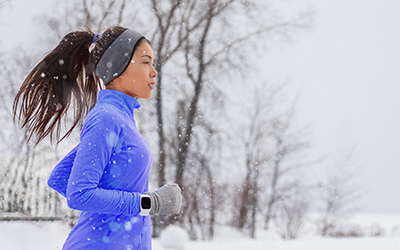 Woman runs as it snows.